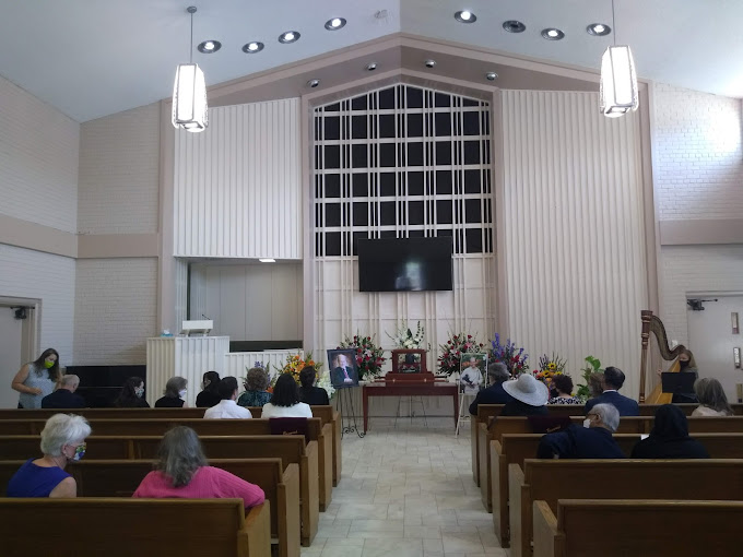 Restland Memorial Park funeral in progress - funeral flowers line the back of the ceremony